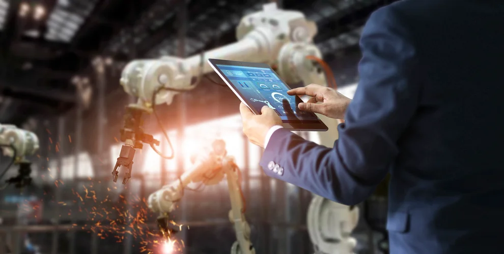 .Manager industrial engineer using tablet check and control automation robot arms machine in intelligent factory industrial on real time monitoring system software. Welding roboticts and digital manufacturing operation. Industry 4.0 concept