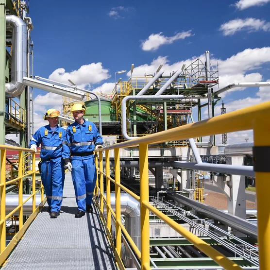 chemical industry plant - workers in work clothes in a refinery with pipes and machinery